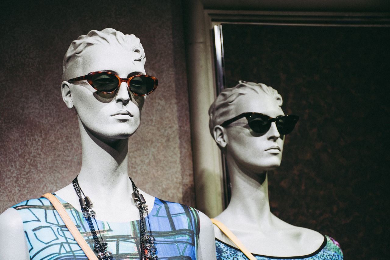 contact-img Elegant mannequins display chic sunglasses and fashionable attire in a retail setting.