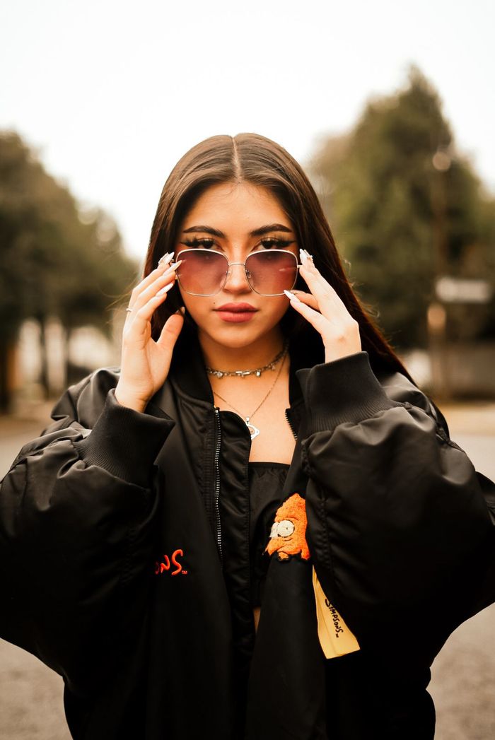 Fashionable young woman wearing sunglasses posing confidently outdoors.