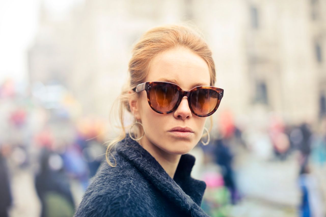 Portrait of a fashionable woman wearing sunglasses in the vibrant streets of Milan, Italy.